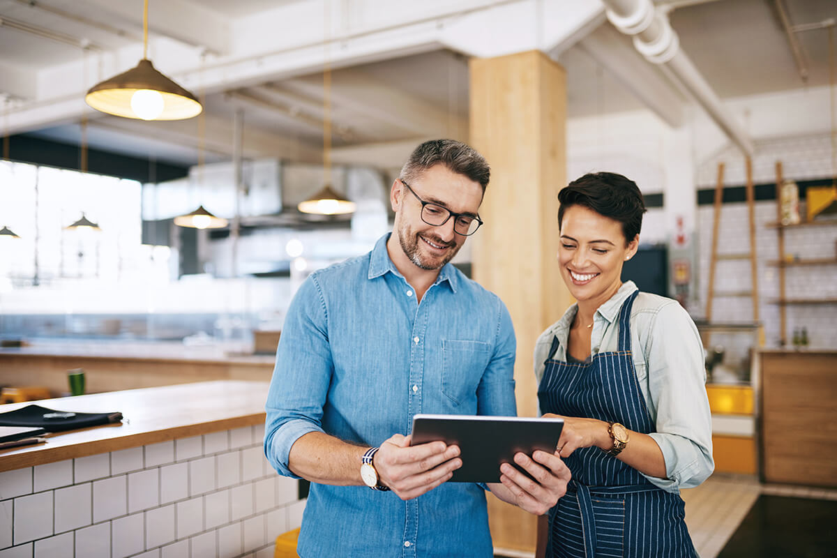 Cafe owners review accounting data on a tablet